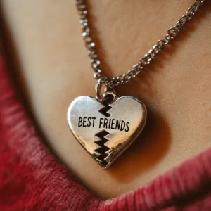 Close-up of a broken heart pendant necklace with 'Best Friends' inscribed, symbolizing friendship betrayal and emotional conflict