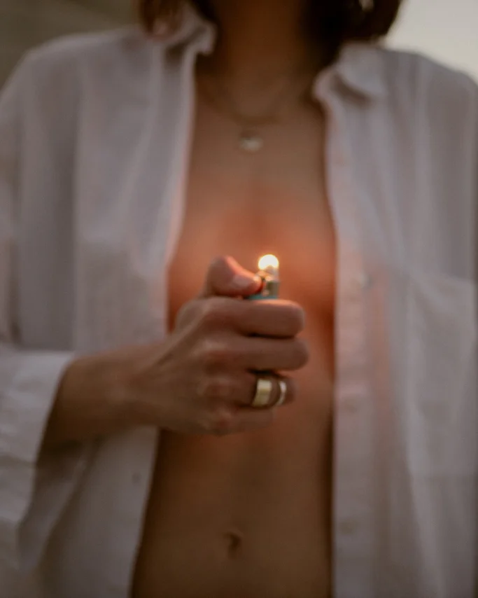 When Should You Burn Bridges with Friends? Scorched Earth to Sacred Self Recovery 2 Woman's torso holding a silver lighter, symbolizing burning bridges and personal empowerment in toxic friendships